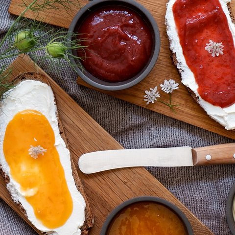 Eco-friendly hotel in Germany with Hirschenmanufaktur Bread with cream cheese and jam on wooden boards with knife and bowls of spreads