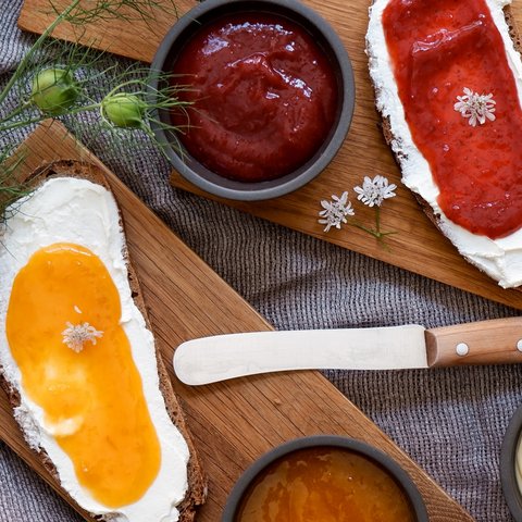 Nachhaltiges Hotel in Bayern mit Hirschenmanufaktur Brot mit Frischkäse und Marmelade auf Holzbrett mit Messermesser und Dips