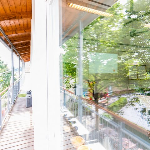 Looking for somewhere for conferences in Bavaria? Hallway with wooden railing and reflective windows beside green trees