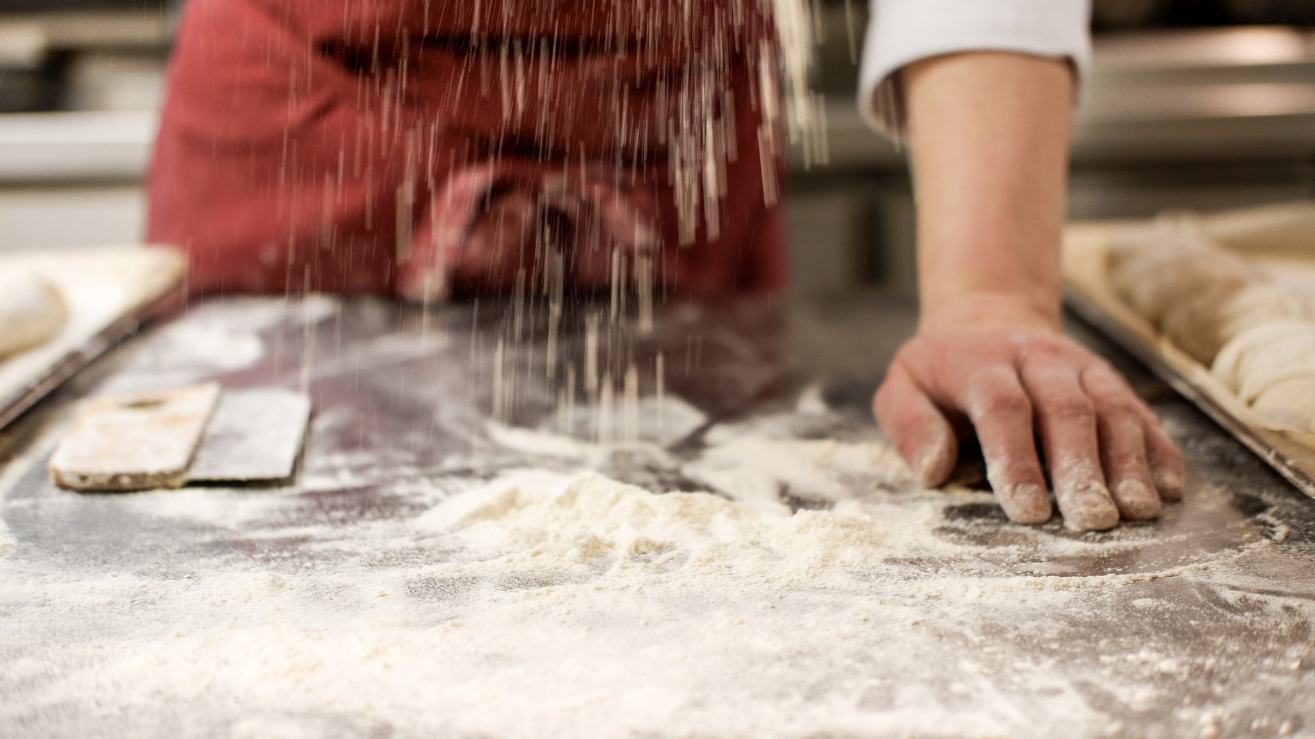 Nachhaltige Hotels in Deutschland gesucht? Person streut Mehl auf Tisch zum Backen