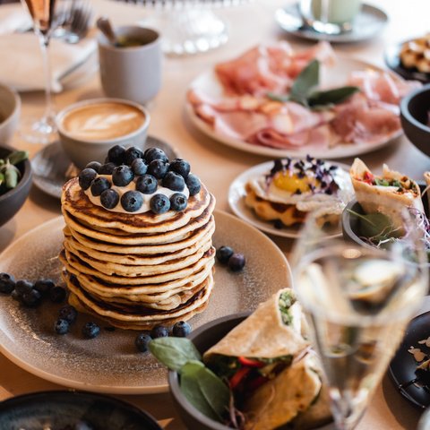 Brunch – breakfast for late risers Table with pancakes, wraps, coffee, and other breakfast dishes