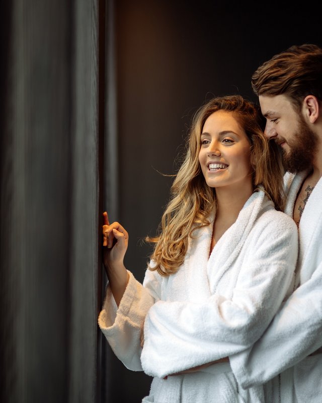 Wellness hotel in Upper Palatinate: Sweat & swim Couple in white bathrobes smiling by the window