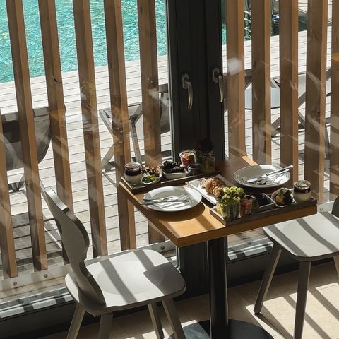 Tageswellness in der Oberpfalz Tisch mit Frühstück und zwei Stühlen neben einem Pool durch Glaswand