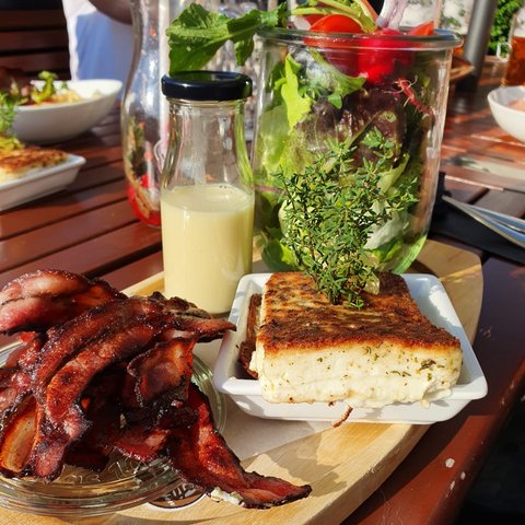 Beer garden in Parsberg: HirschenBlobb Grilled cheese, bacon, salad, and dressing on a wooden outdoor table