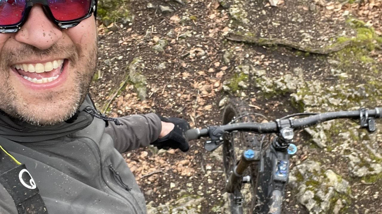Man wearing helmet and sunglasses mountain biking on mossy forest trail