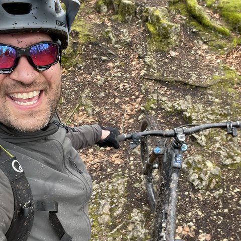 Hotel mit Fahrradverleih in Bayern gesucht? Mann mit Helm und Sonnenbrille beim Mountainbiken auf moosigem Waldweg