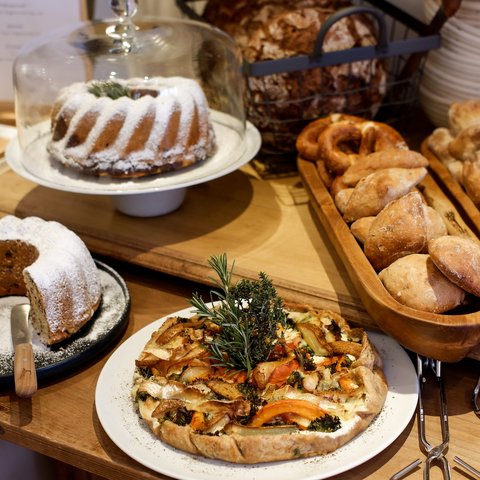 Romantik Hotel Hirschen: Frühstück Verschiedene Backwaren wie Gugelhupf, Brot, Brezeln und Gemüsetarte auf Holztisch