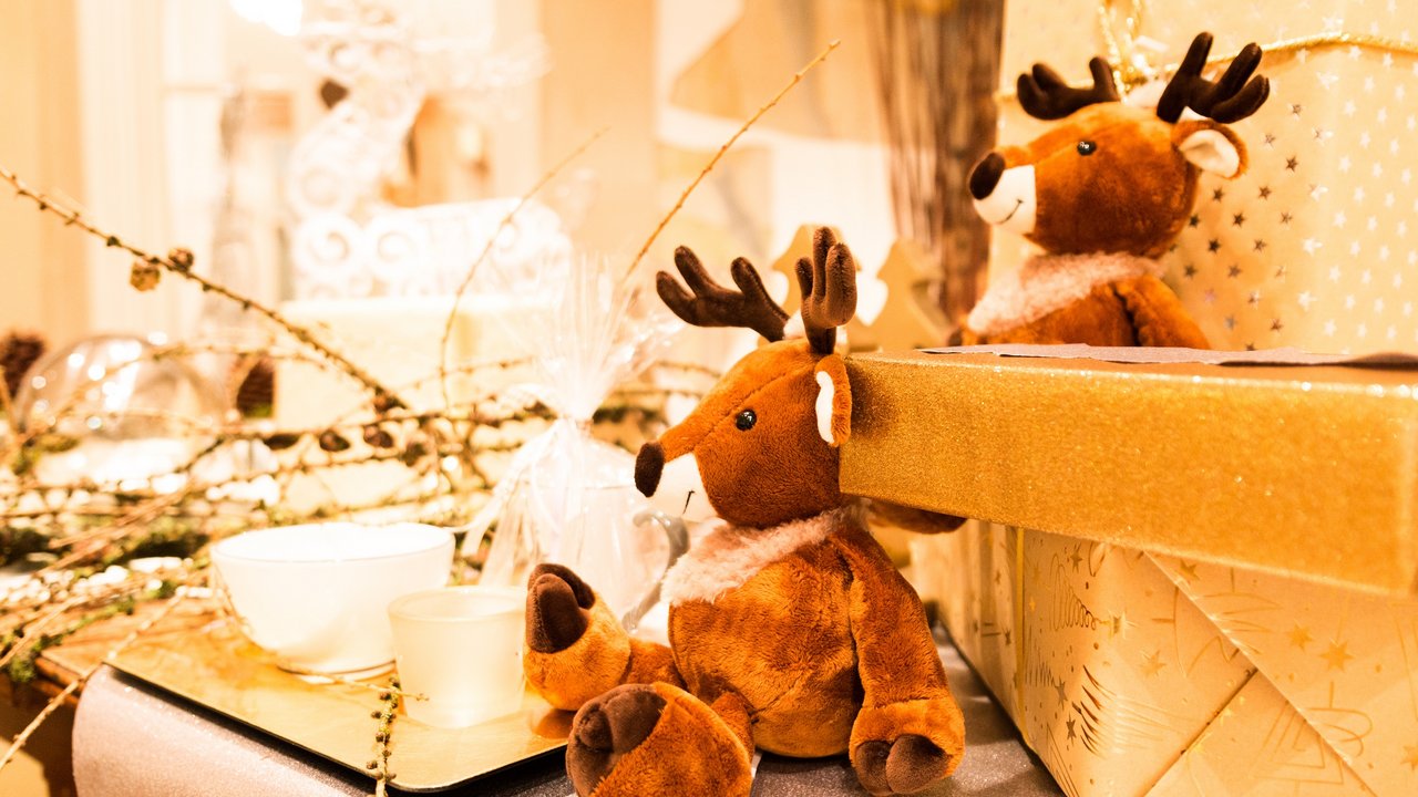 Weihnachtliche Dekoration mit Plüschrentieren und Geschenkboxen in warmem Licht