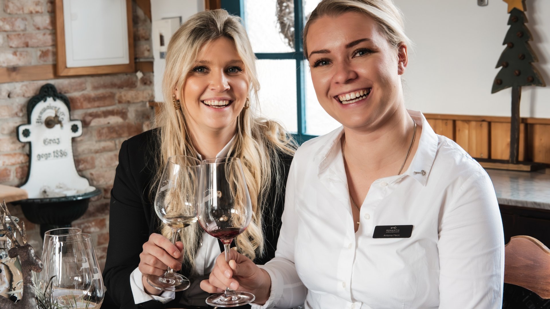 Event calendar 2026 Two women clinking wine glasses in a cozy restaurant