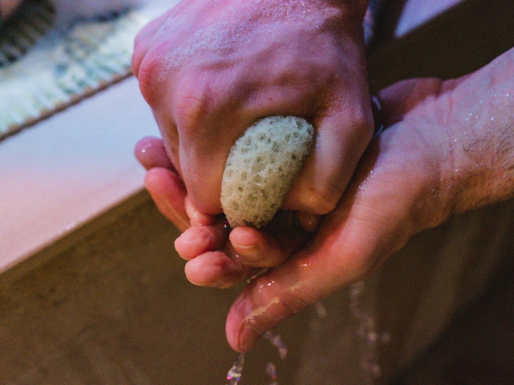 Wellness Hände waschen mit einem natürlichen Schwamm über einem Waschbecken