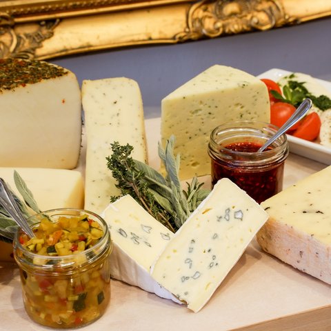 Romantik Hotel Hirschen: Frühstück Vielfalt an Käsesorten mit Kräutern, Marmelade und Tomaten auf Holzbrett