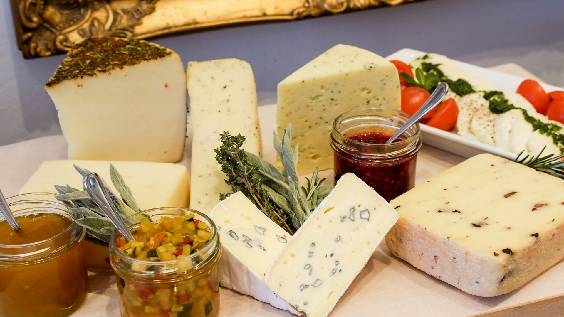 Romantik Hotel Hirschen: Frühstück Vielfalt an Käsesorten mit Kräutern, Marmelade und Tomaten auf Holzbrett