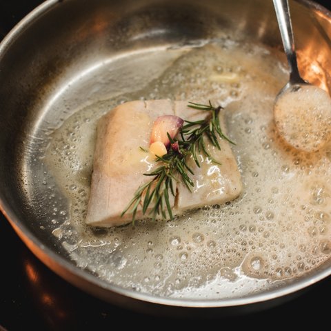 Workation Fischfilet mit Knoblauch und Rosmarin in einer Pfanne mit Butter gebraten