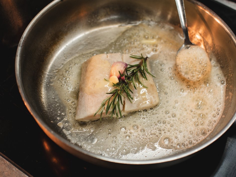 Nachhaltige Hotels in Deutschland gesucht? Fischfilet mit Knoblauch und Rosmarin in einer Pfanne mit Butter gebraten