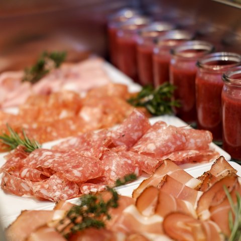 Romantik Hotel Hirschen: Frühstück Verschiedene dünn geschnittene Wurstsorten auf weißen Tellern mit kleinen Gläsern roter Soße
