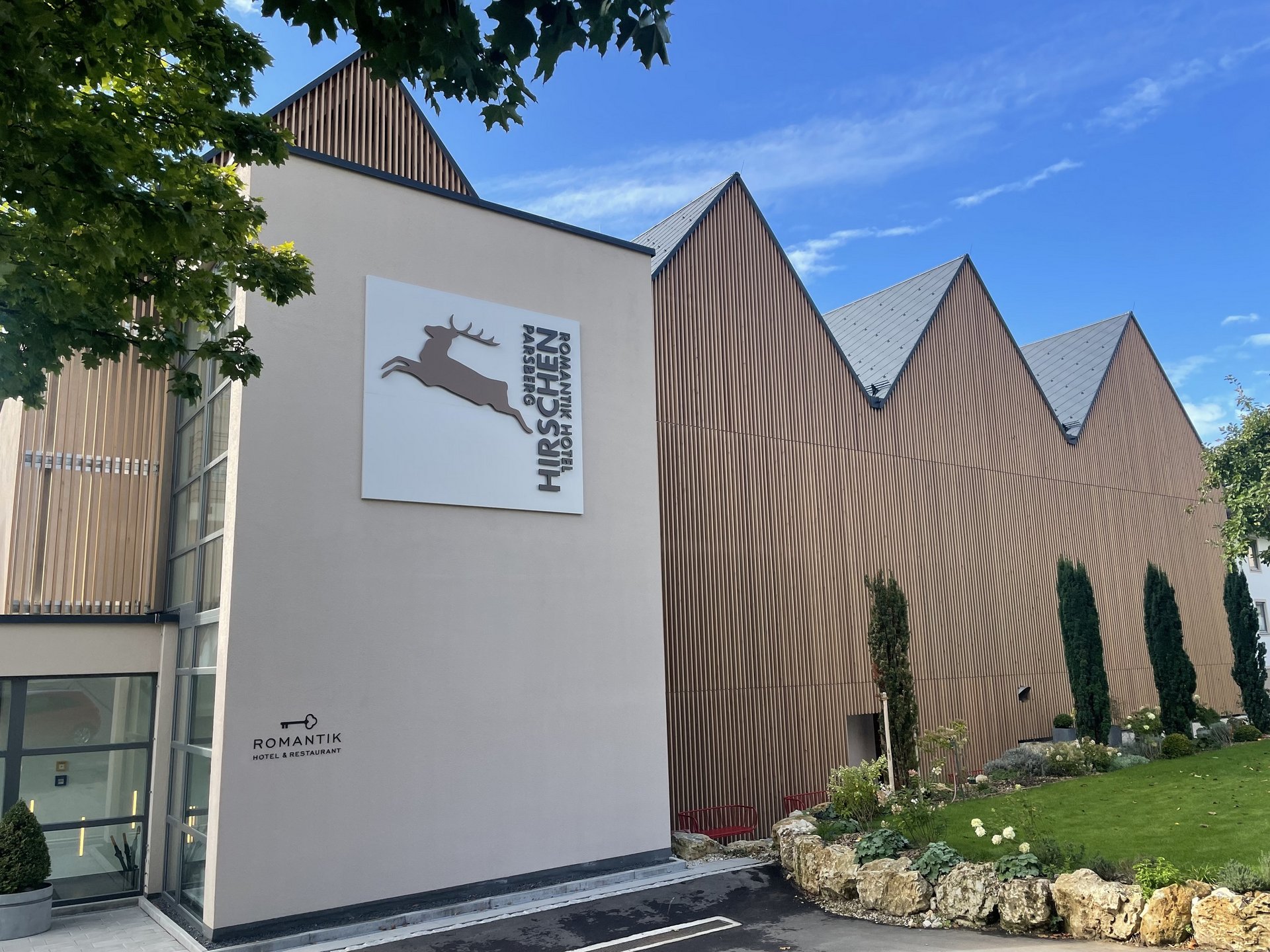 Tagungshotel in der Oberpfalz mit modernen Tagungsräumen Ansicht des Romantik Hotel Hirschen mit moderner Holzfassade bei Sonnenschein