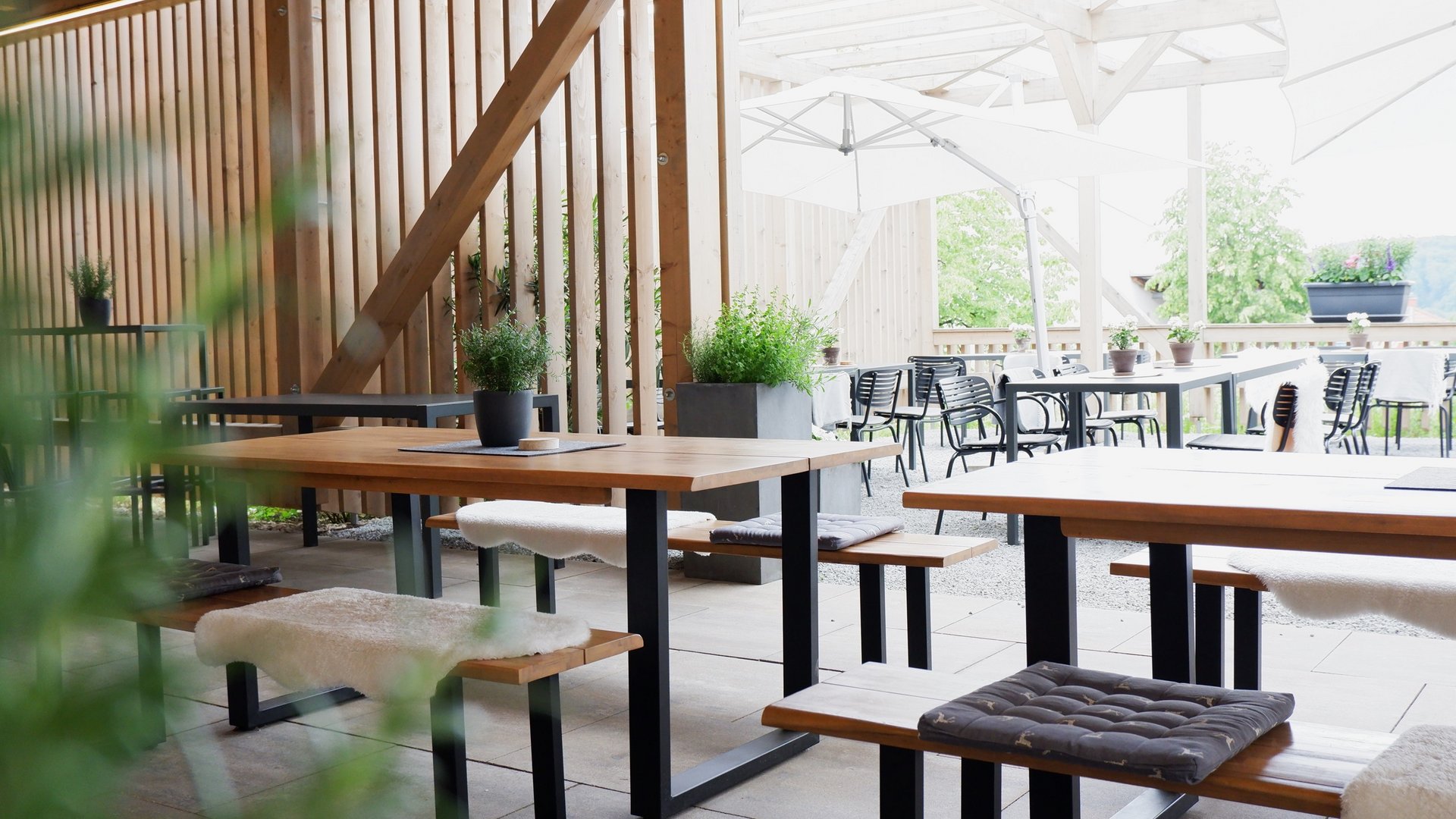 Beer garden in Parsberg: HirschenBlobb Cozy outdoor patio with wooden tables, seat cushions, and plants