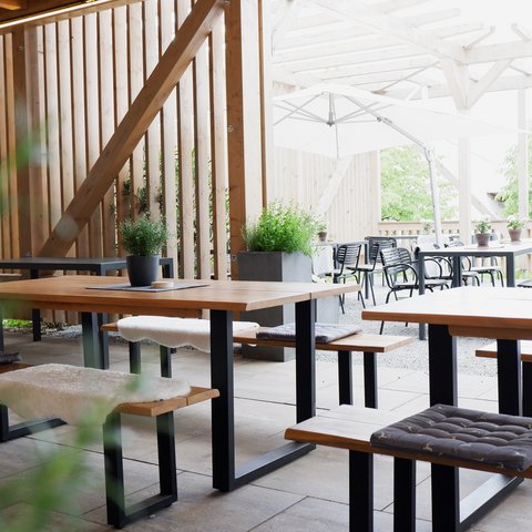 Beer garden in Parsberg: HirschenBlobb Cozy outdoor patio with wooden tables, seat cushions, and plants