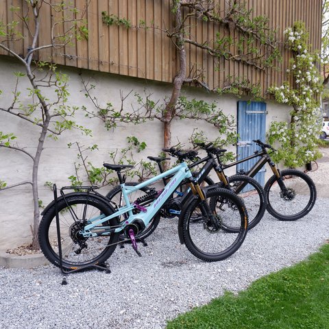 Looking for a hotel with bike rental in Bavaria? Three mountain bikes parked in front of a wooden house with flowering plants