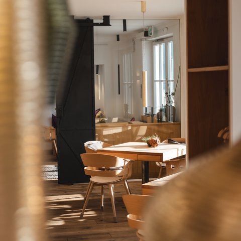 Restaurant in Parsberg: Gourmet genießen Helles, modern eingerichtetes Zimmer mit Holztischen und Stühlen.