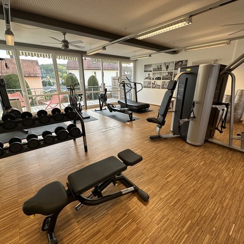 Day wellness in Upper Palatinate Bright gym room with workout machines and dumbbells by large windows