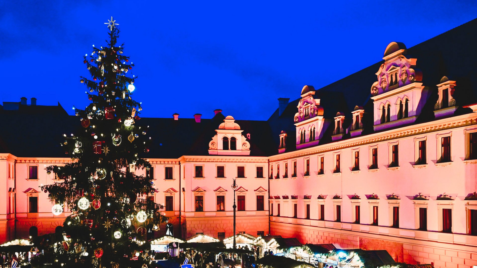 Weihnachtsmärkte Weihnachtsmarkt bei Nacht mit festlich geschmücktem Baum, Marktständen und historischem Gebäude