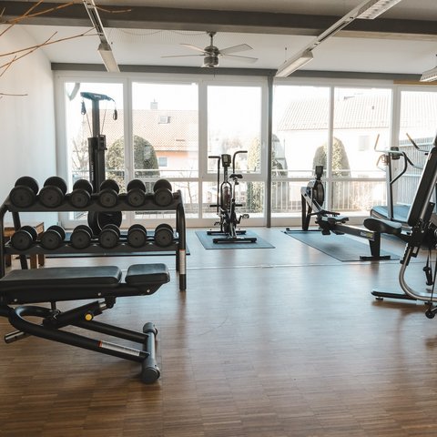 Fitnessraum Modern gym room with dumbbells, exercise bikes, and workout bench