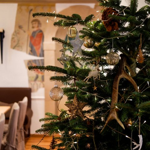 Gasthof Parsberg: Ein Gruß an den guten Geschmack Weihnachtsbaum mit Dekoration aus Holzsternen und Geweih in einem gemütlichen Raum