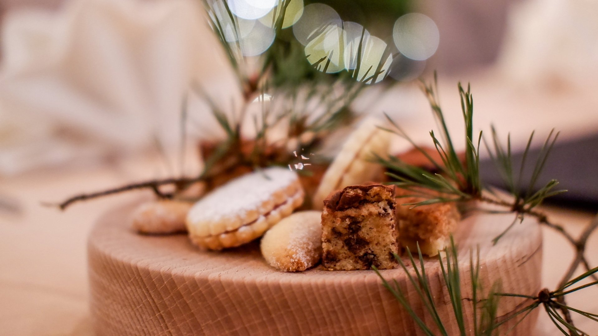 Weihnachtsmenüs 2025 Verschiedene Weihnachtskekse auf Holzbrett mit Tannenzweigen und Lichterbokeh