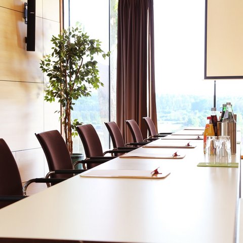 Tagungshotel Oberpfalz: Das Hotel für Deine Tagung Moderner Besprechungsraum mit Stühlen und großem Tisch vor Fenster