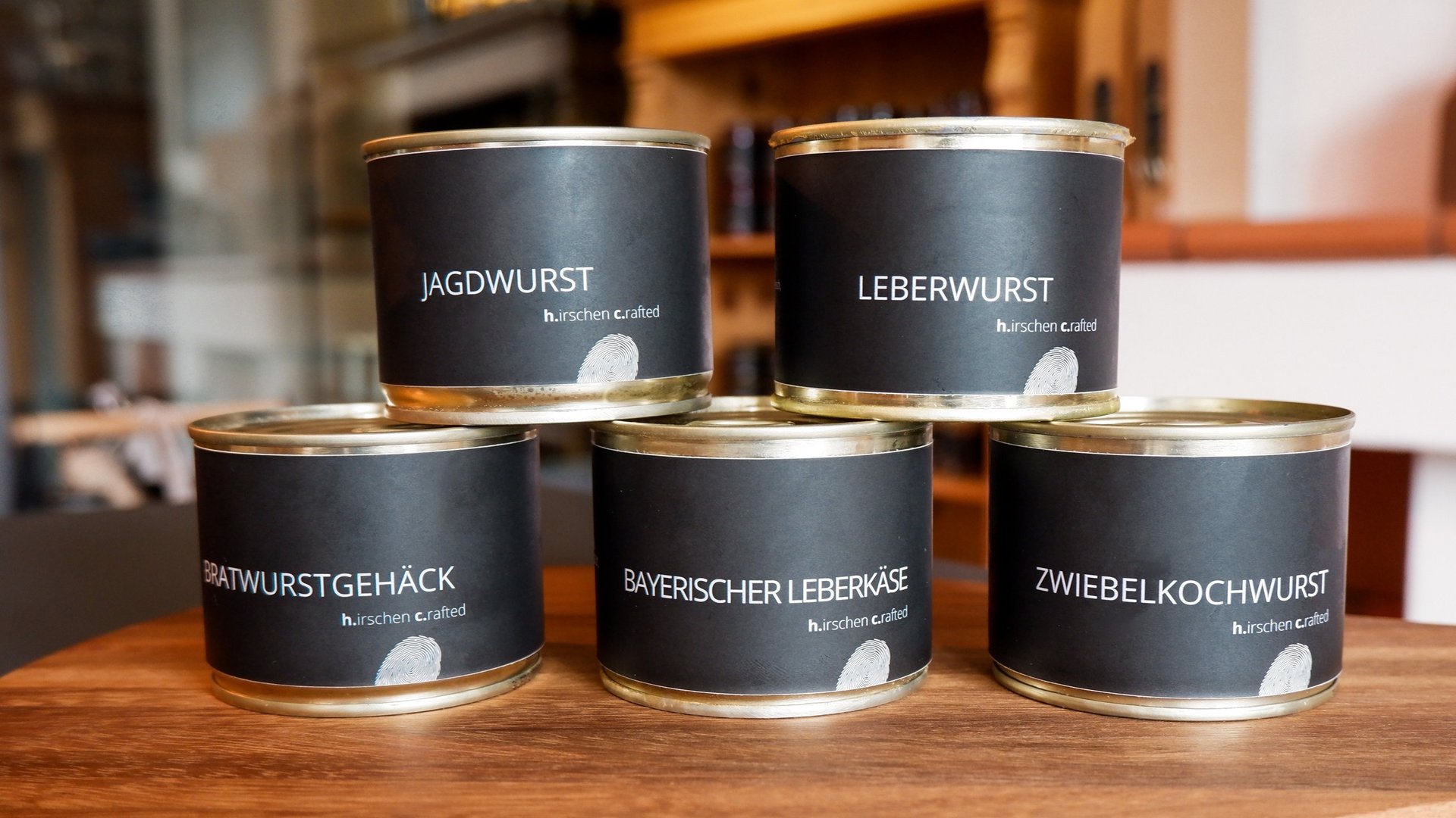Nachhaltige Hotels in Deutschland gesucht? Fünf Dosen mit verschiedenen Wurstsorten auf einem Holzbrett