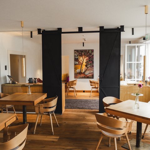 Restaurant in Parsberg: Gourmet genießen Gemütliches Restaurant mit Holztischen und Stühlen, Blumendekoration und Kunst an der Wand