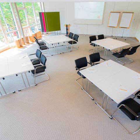 Looking for somewhere for conferences in Bavaria? Bright conference room with several tables, chairs, and notepads