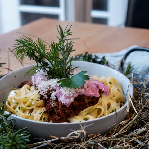 Gasthof Parsberg: Ein Gruß an den guten Geschmack Nudeln mit Bolognese, Käse und Kräutern serviert in einer Schale auf einem Tisch