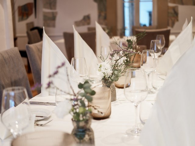 Romantik Hotel Hirschen: Kulinarik Eleganter gedeckter Tisch mit weißen Servietten und Blumen in Vasen