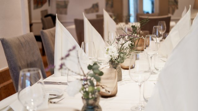 Nachhaltiges Hotel in Bayern mit Hirschenmanufaktur Eleganter gedeckter Tisch mit weißen Servietten und Blumen in Vasen