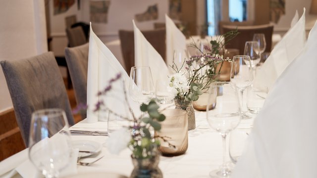 Nachhaltiges Hotel in Bayern mit Hirschenmanufaktur Eleganter gedeckter Tisch mit weißen Servietten und Blumen in Vasen