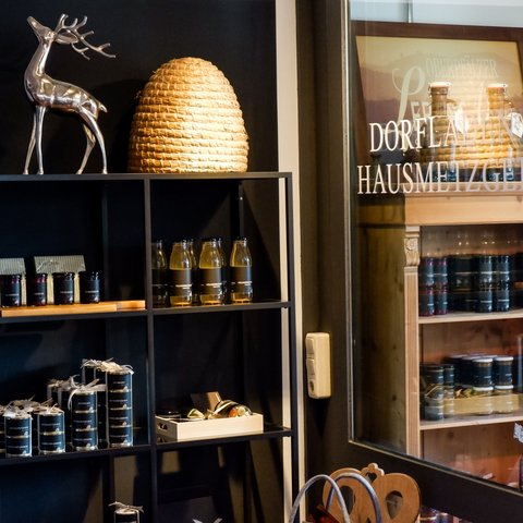 Eco-friendly hotel in Germany with Hirschenmanufaktur Shelf with jars, bottles, and decor next to glass door with lettering