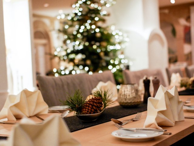 Romantik Hotel Hirschen: Bildergalerie Festlich gedeckter Esstisch mit Weihnachtsbaum und Lichterketten im Hintergrund