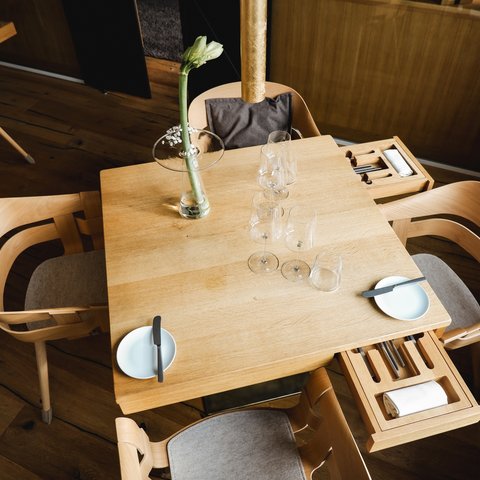 Restaurant in Parsberg: Gourmet genießen Holztisch mit vier Stühlen, Gläsern, Tellern und einer Blume in Vase
