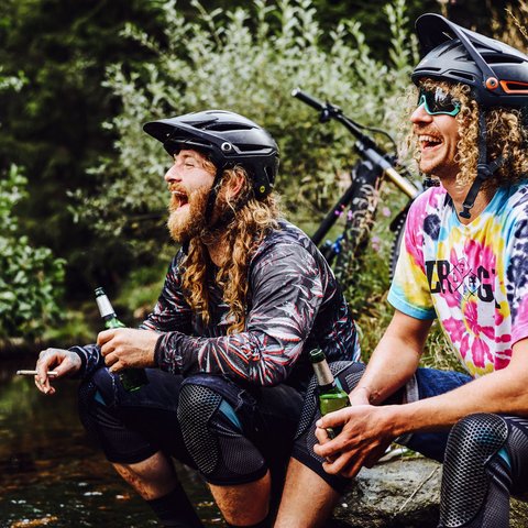 Hotel mit Fahrradverleih in Bayern gesucht? Zwei Männer mit Fahrradhelmen trinken Bier und lachen im Grünen