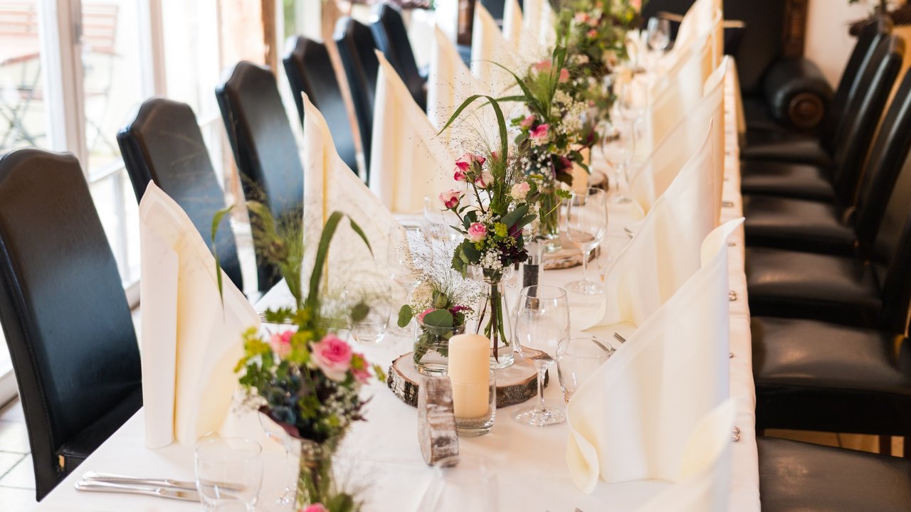 Herbsthochzeit in der Oberpfalz Festlich gedeckter Tisch mit weißen Servietten, Blumenarrangements und Kerzen
