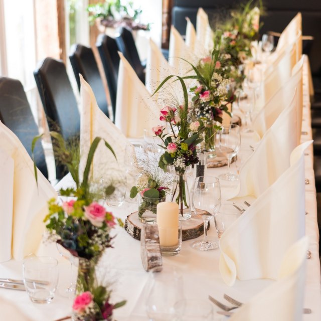 Hochzeitslocation Oberpfalz gesucht? Festlich gedeckter Tisch mit weißen Servietten, Blumenarrangements und Kerzen