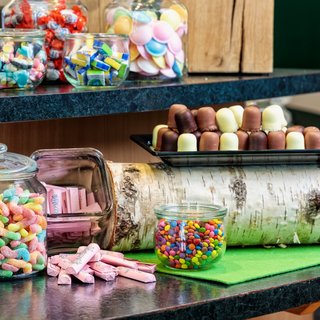 Leistungen und Preise für Tagungen und Konferenzen Gläser mit bunten Süßigkeiten und Schokoladen auf einer Theke