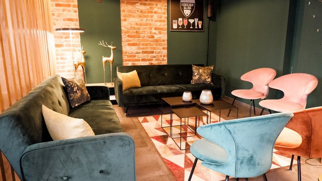 Romantik Hotel Hirschen: Blog Gemütliches Wohnzimmer mit grünen Sofas und bunten Stühlen vor Backsteinwand
