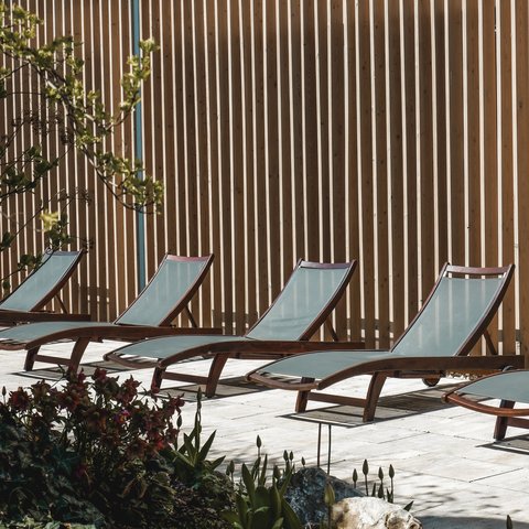Tageswellness in der Oberpfalz Leere Liegestühle vor einer Holzlattenwand neben einem Beet mit Pflanzen