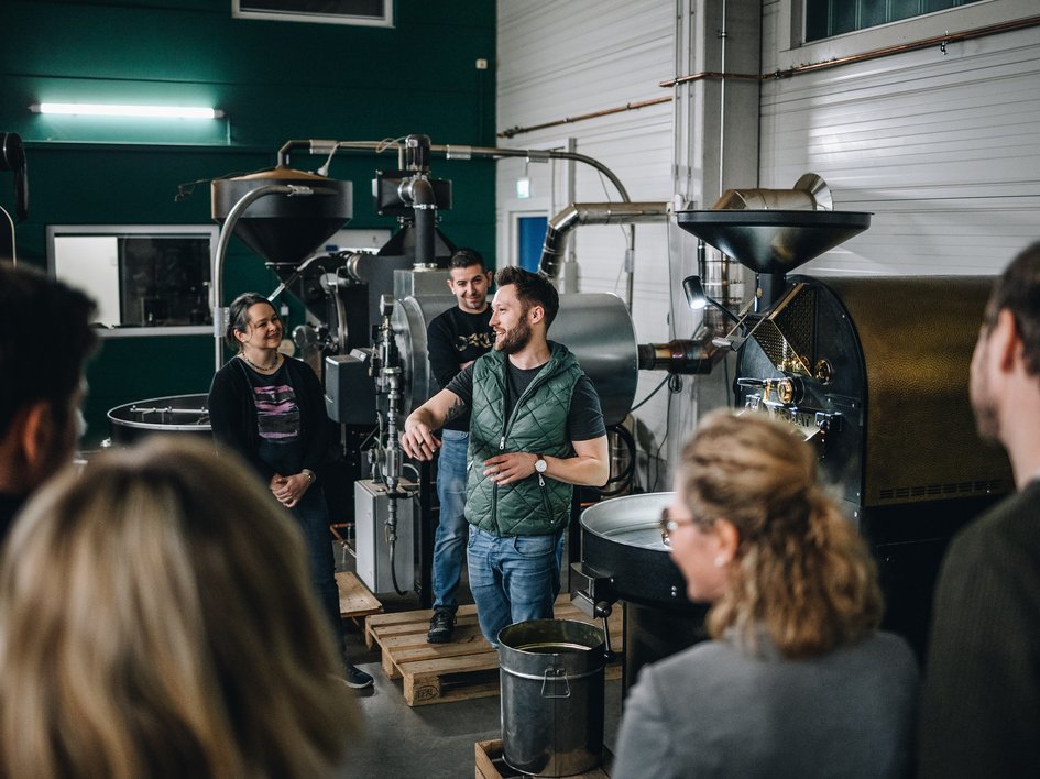 Tagungshotel mit Events gesucht? Gruppe bei einer Führung durch eine Kaffeerösterei mit Maschinen im Hintergrund