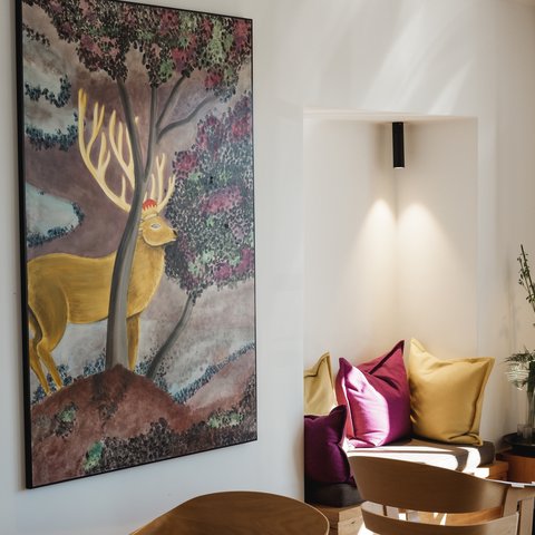 Restaurant in Parsberg: Gourmet genießen Gemälde eines Hirsches an der Wand neben bequemen Sesseln und Kissen in einer modernen Sitzecke