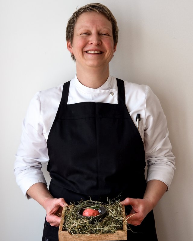 Hirschenblobb: unsere Bar Lächelnder Koch präsentiert Gourmetgericht auf Heubett auf Holztablett