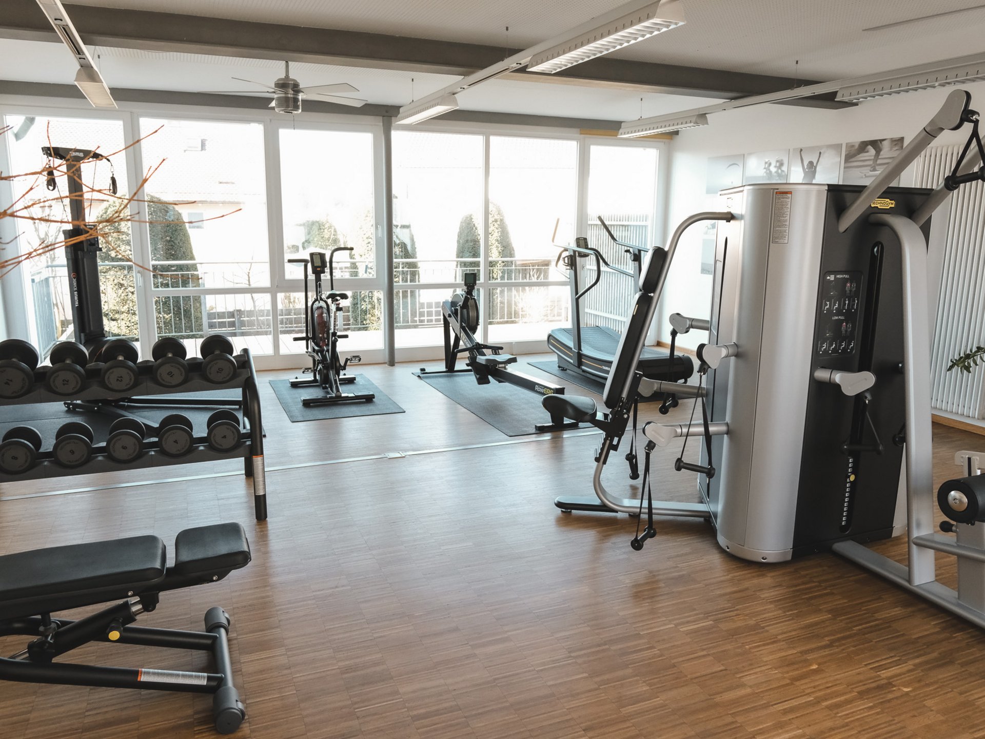 Everything you need for your stay. Modern gym with workout machines and dumbbells near large windows